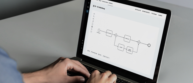 Bild von einem Laptop, an dem eine Person gerade dank Low Code schnell & effektiv BPMN 2 0 Diagramme erstellt