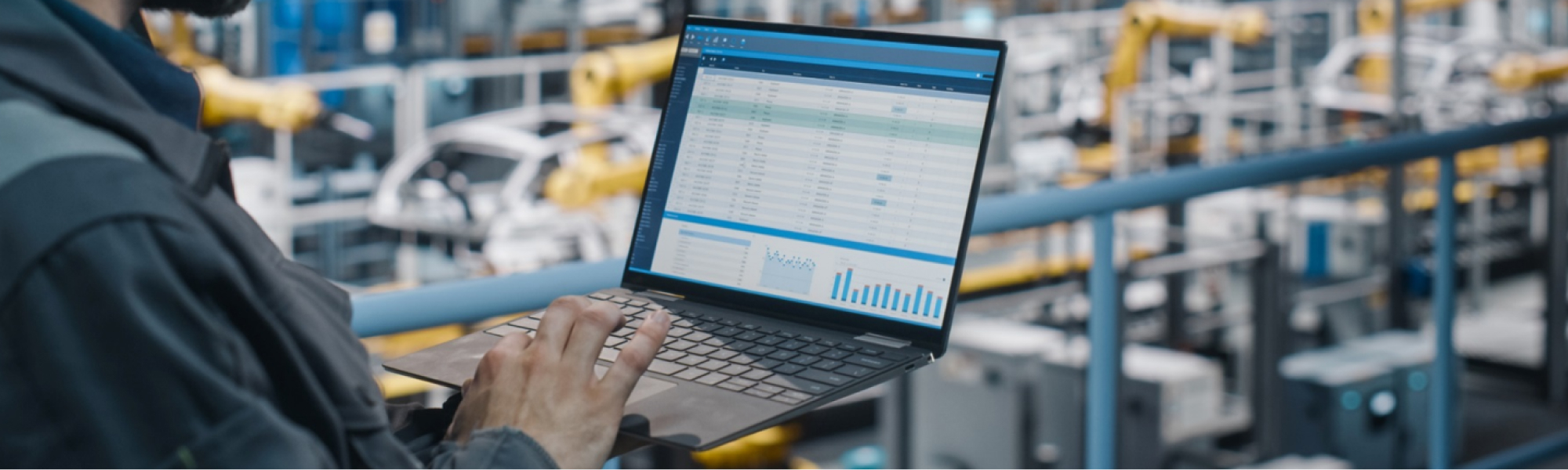 Person in a production facility checking some data on a laptop