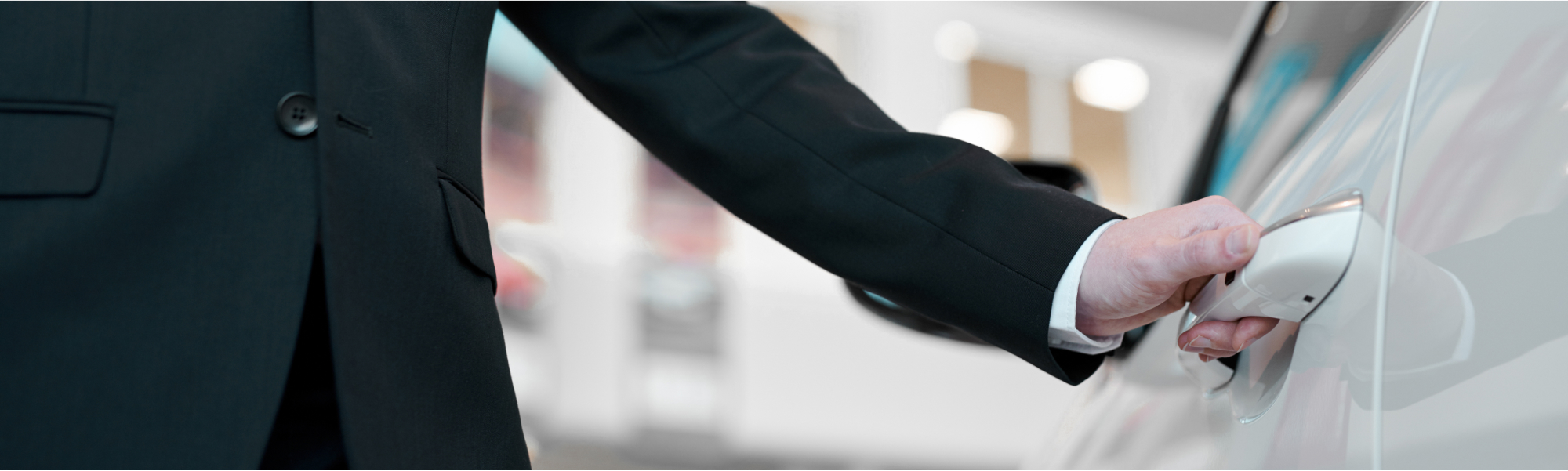 Person hält den Griff eines weißen Autos in der Hand