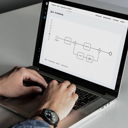 Bild von einem Laptop, an dem eine Person gerade dank Low Code schnell & effektiv BPMN 2 0 Diagramme erstellt